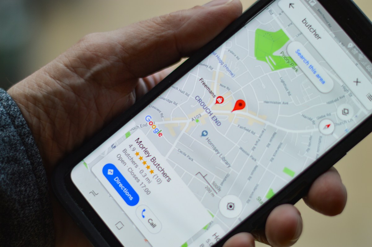 Main tenant un smartphone affichant une carte Google Maps (butcher).