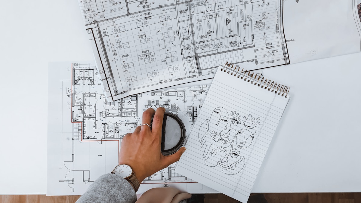 Plans architecturaux, croquis, main tenant une loupe.