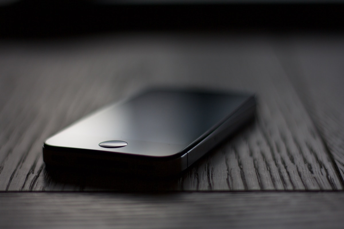 Smartphone noir sur une surface en bois sombre.