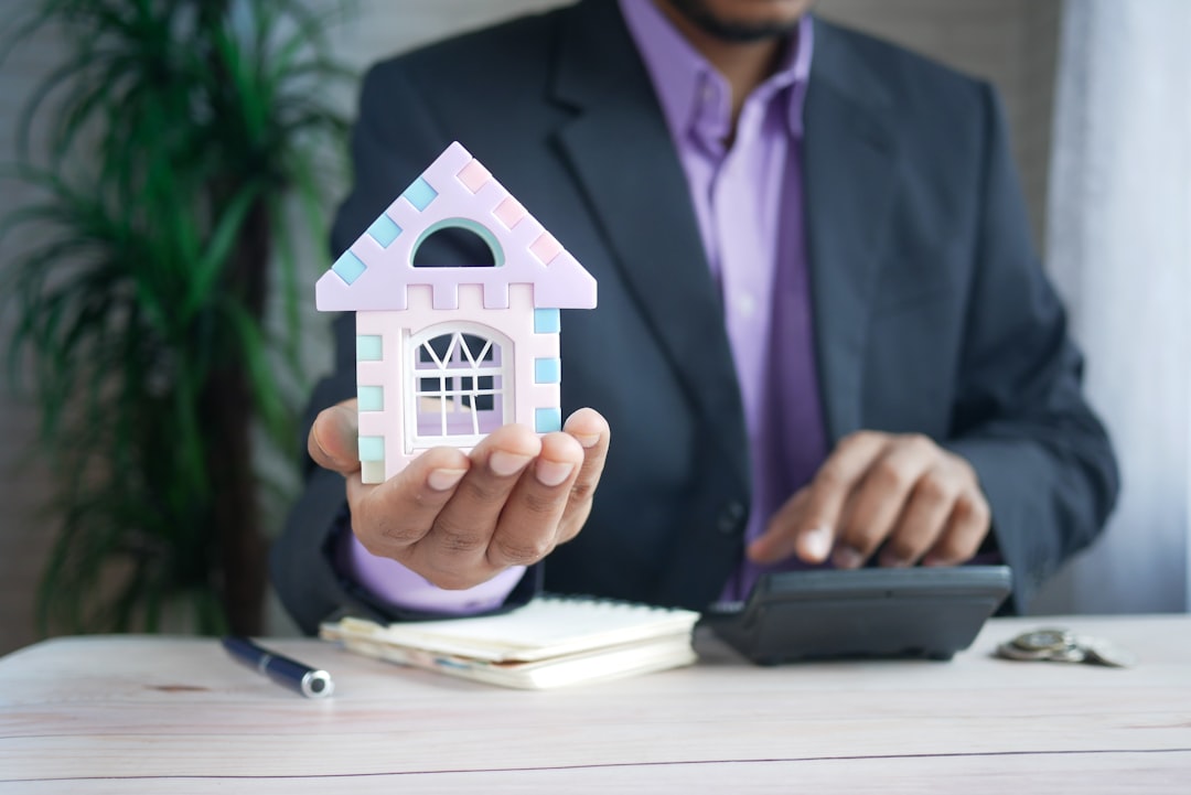 tendance immobilier connecté 2026 - man holding model house at desk with calculator