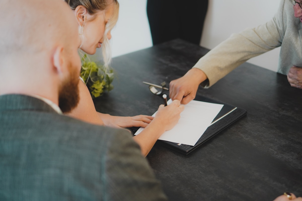 Deux personnes signant un document officiel sur un bureau noir.