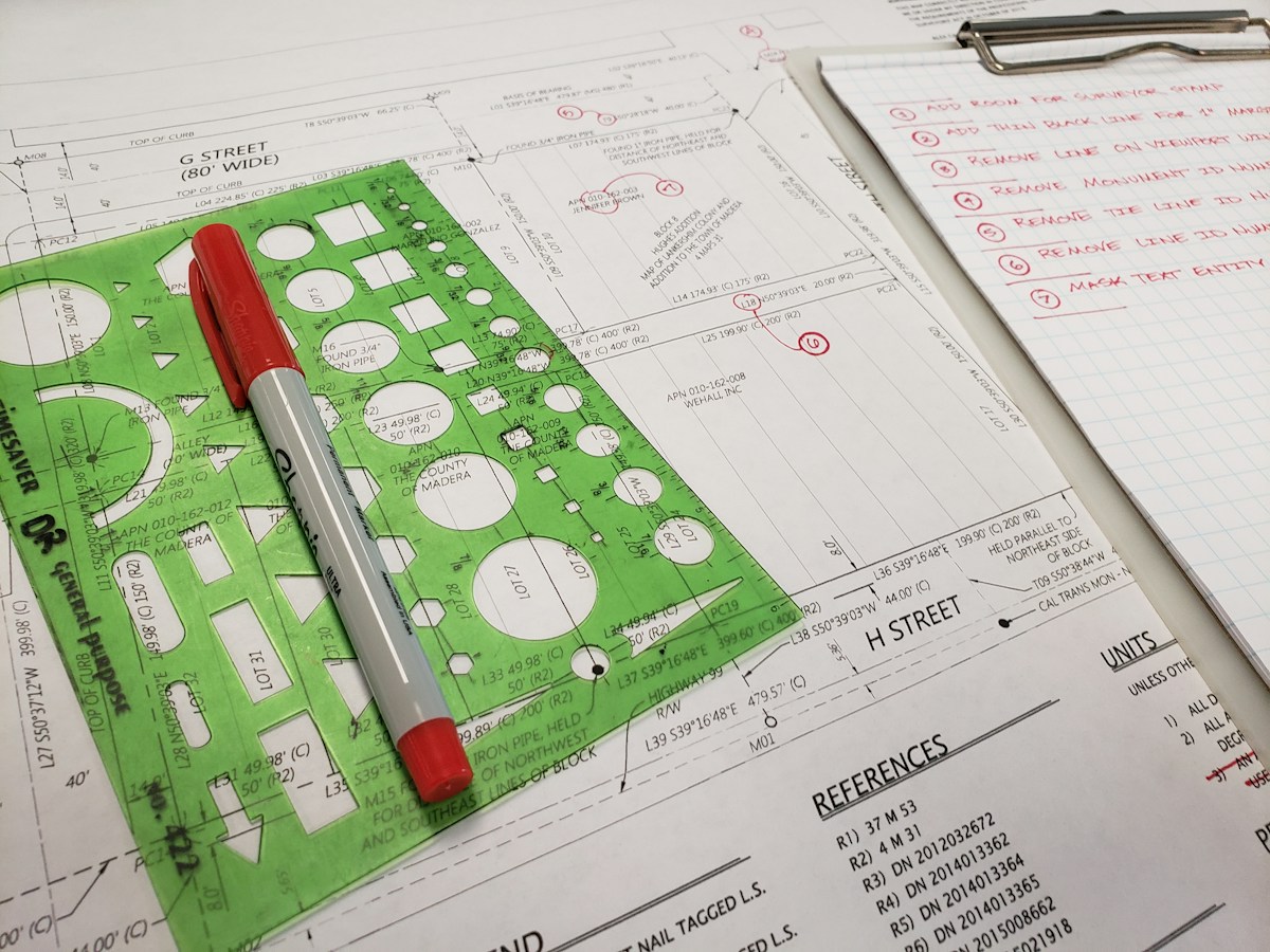 Plan d’arpentage avec surligneur rouge, règle verte et notes manuscrites.