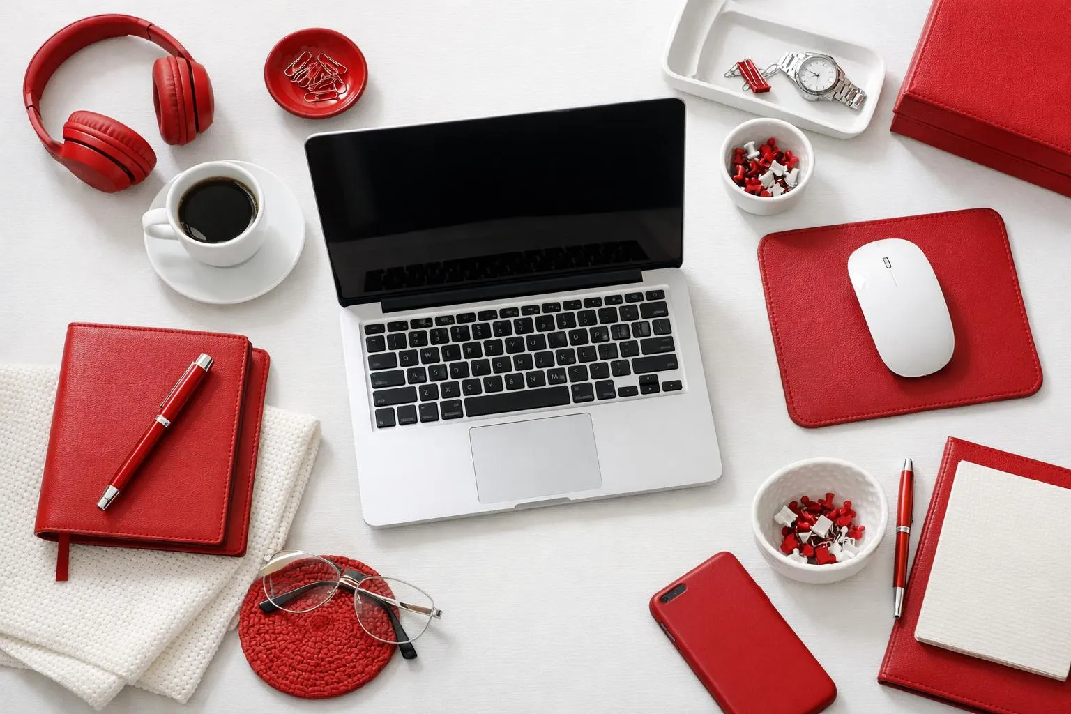 Bureau de travail avec ordinateur portable et accessoires rouges.