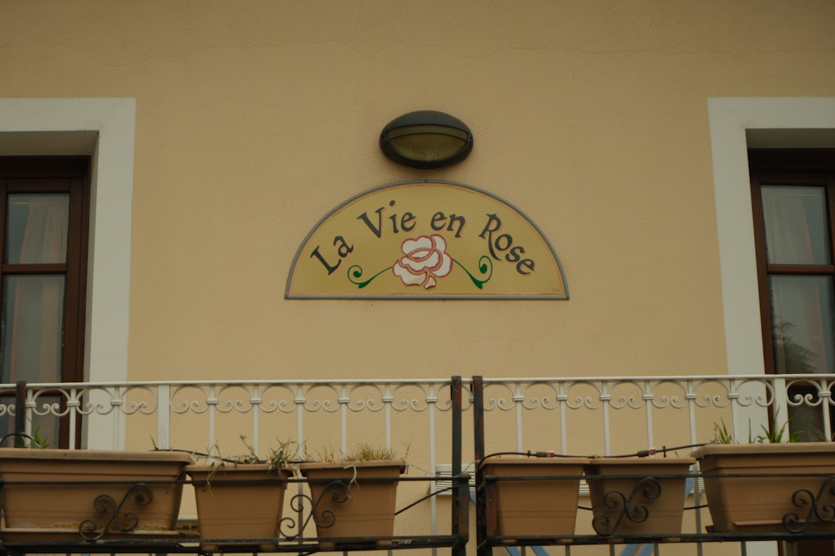 Enseigne de restaurant "La Vie en Rose" avec une fleur rose.
