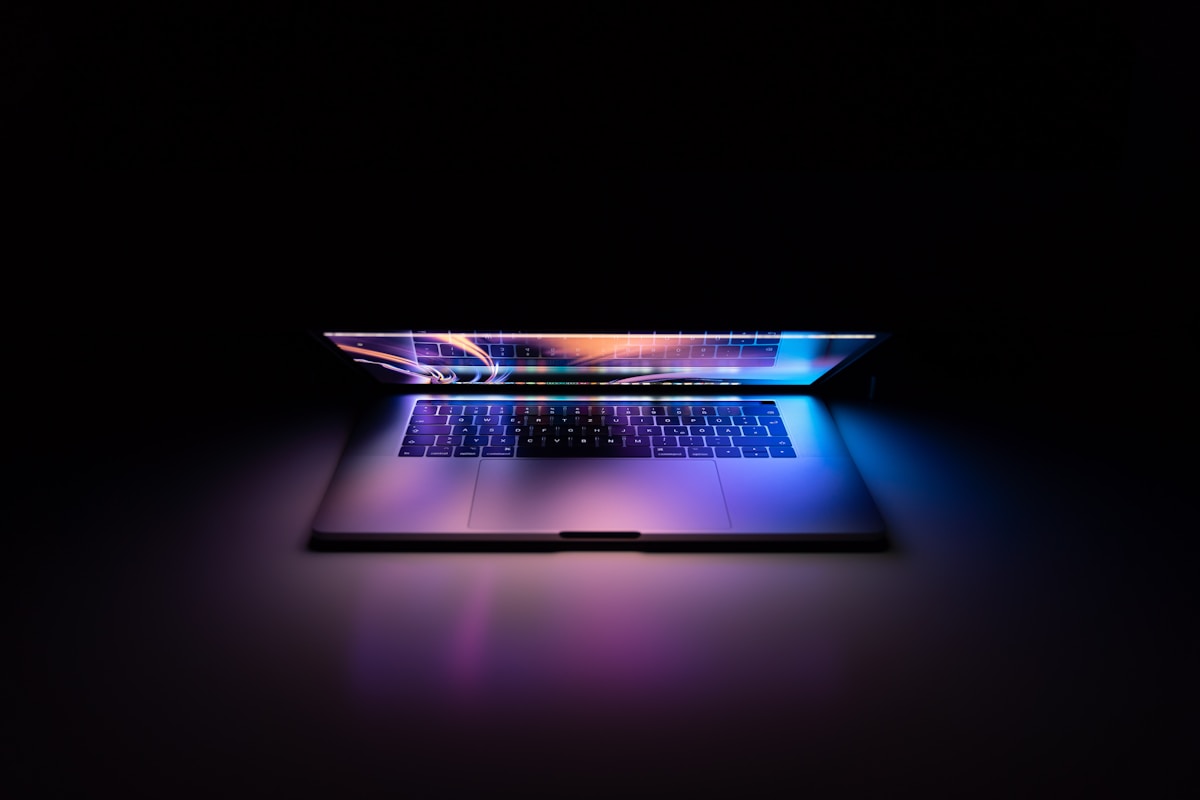 Ordinateur portable sombre avec clavier lumineux et écran coloré.
