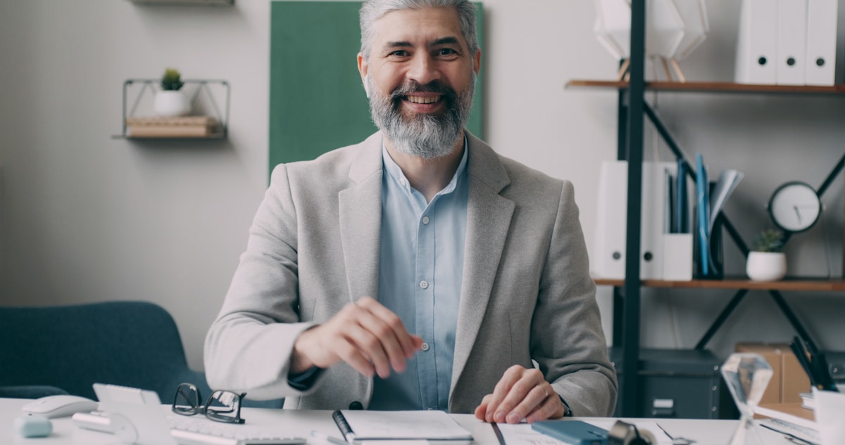Un homme d'affaires mature et souriant, assis à son bureau.