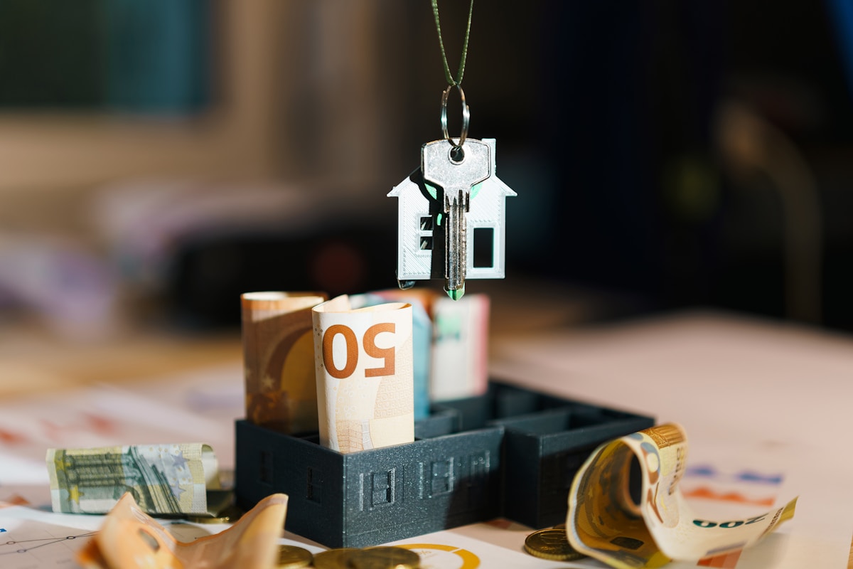 Clé de maison suspendue avec billets et pièces de monnaie sur la table.