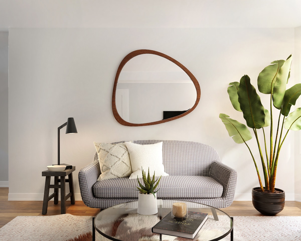 Salon moderne avec miroir ovale, canapé à motifs et plante décorative.