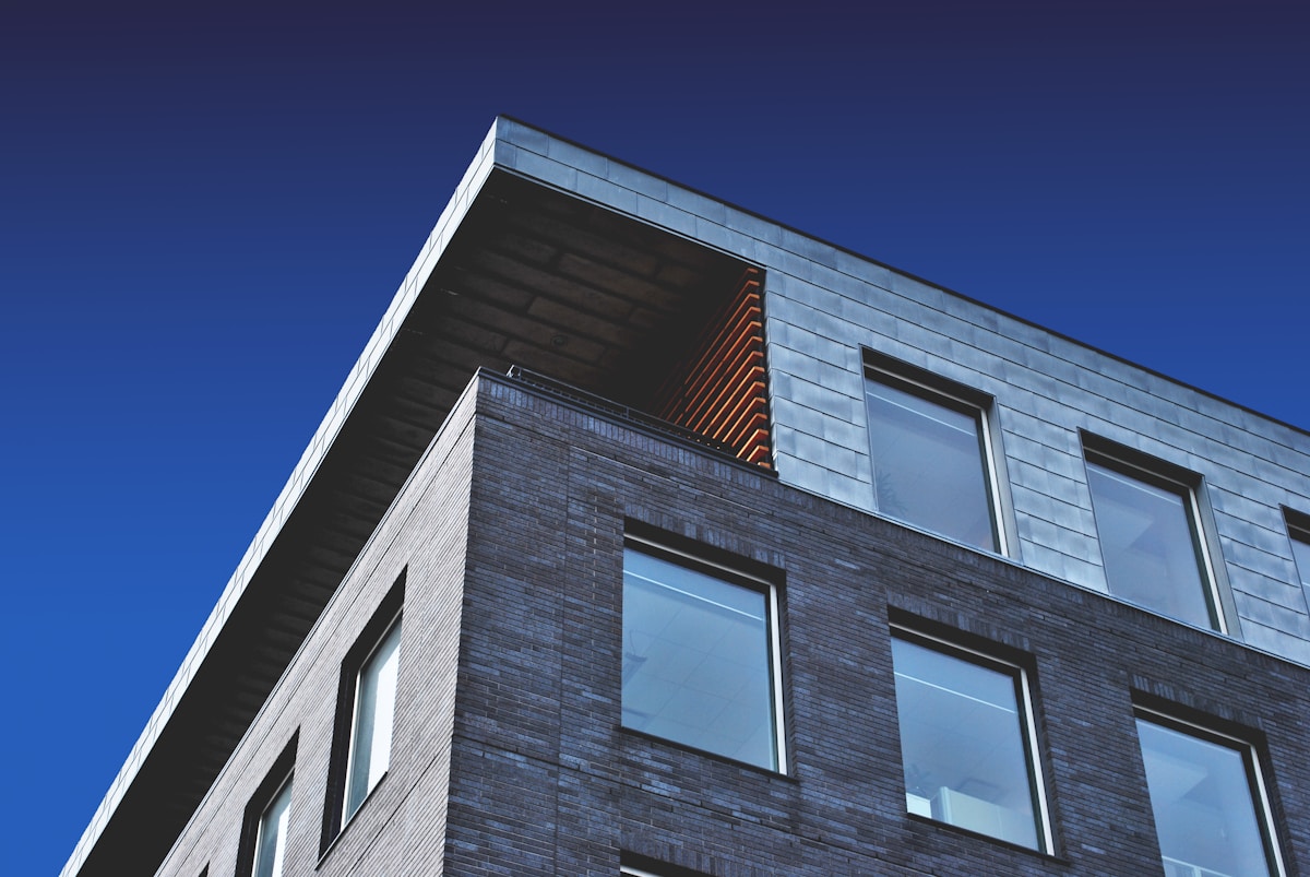 Bâtiment moderne en briques grises avec fenêtres et détails en bois.