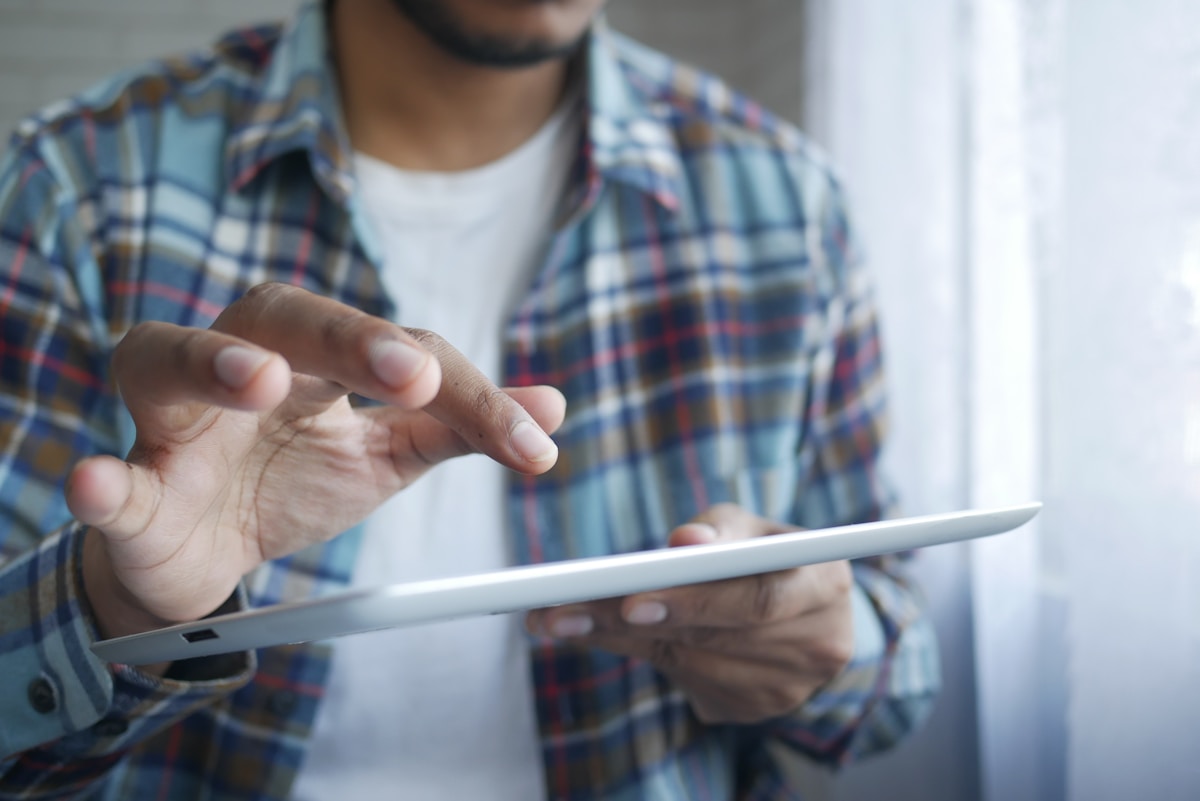 Homme utilisant une tablette numérique dans un environnement intérieur.
