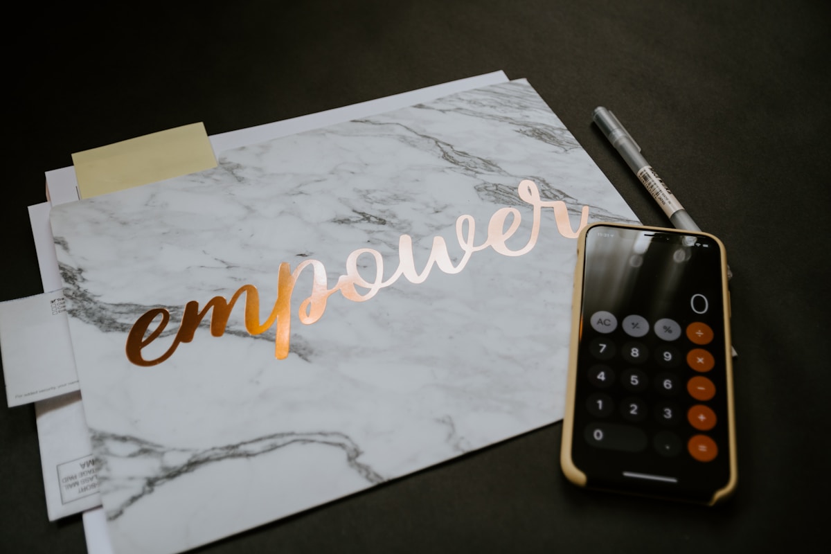 Papiers, calculatrice et texte "Empower" sur fond de marbre.