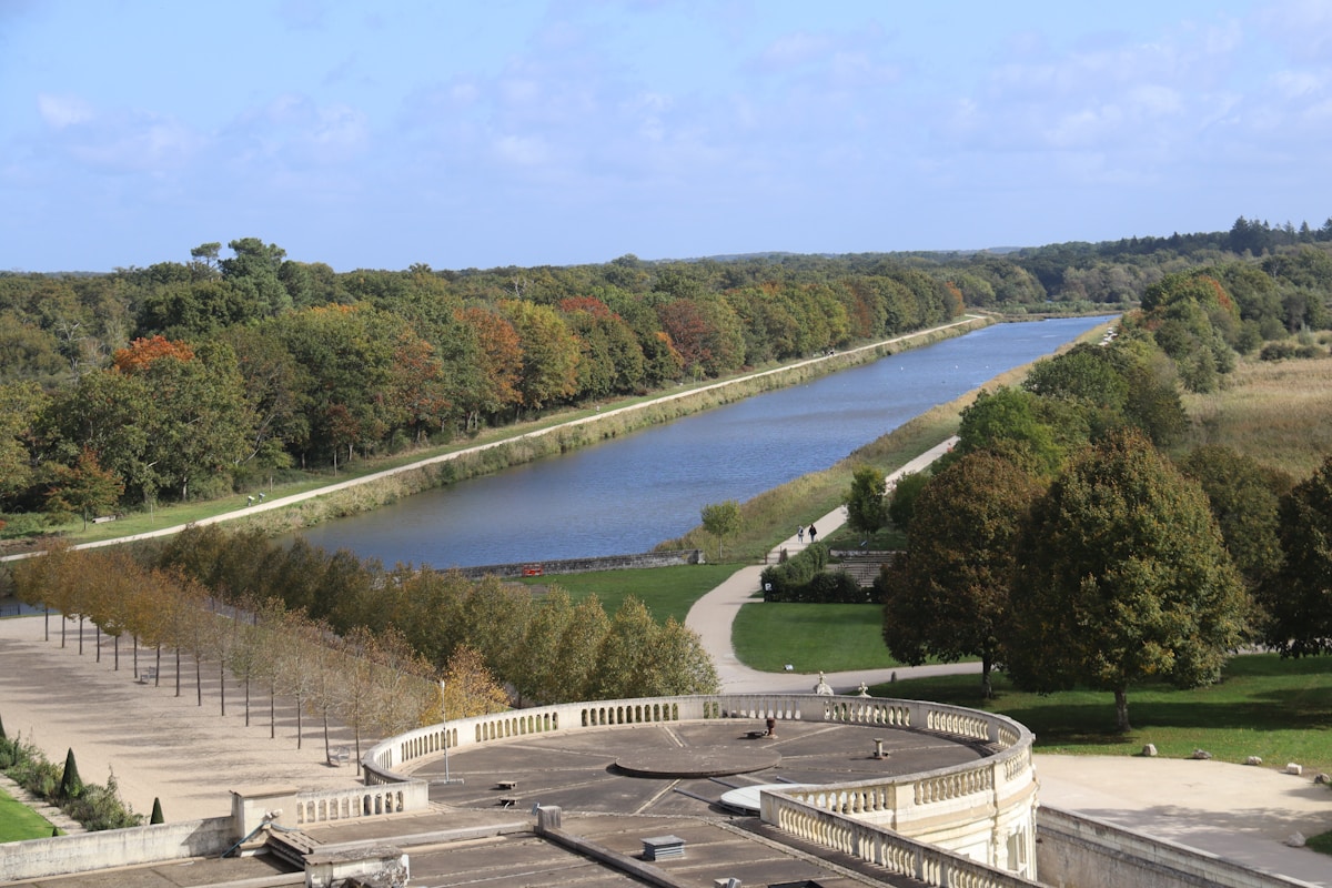 Paysage automnal avec rivière, forêt et promenade le long de l'eau.