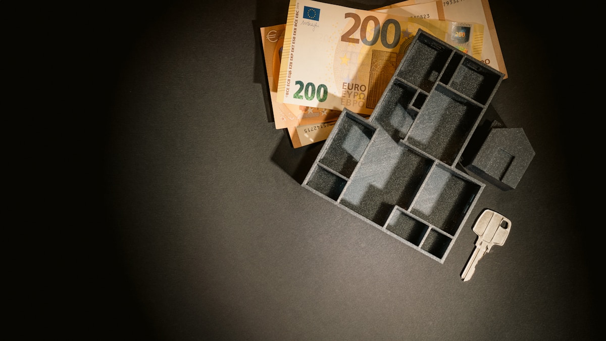 Billets en euros, clé et motif géométrique abstrait.