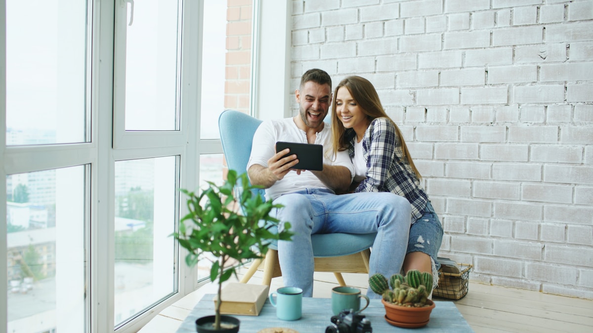 Couple heureux regardant un téléphone portable ensemble dans un intérieur lumineux.