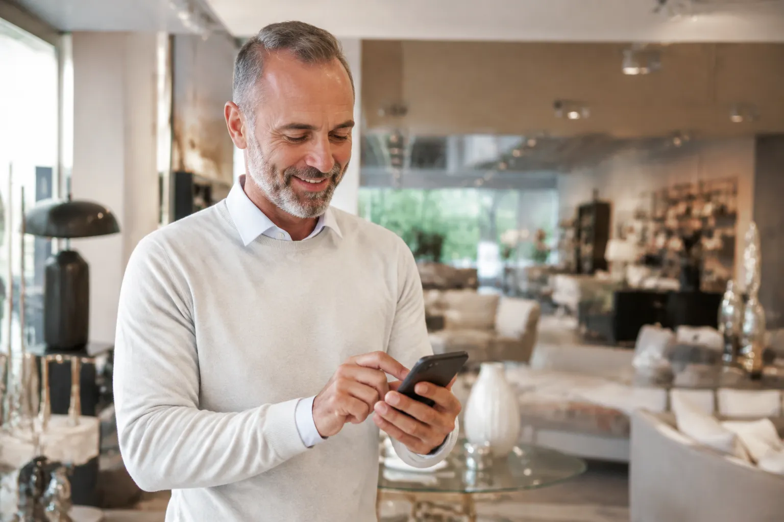 Un homme d'affaires mature utilisant un téléphone portable dans un salon moderne.