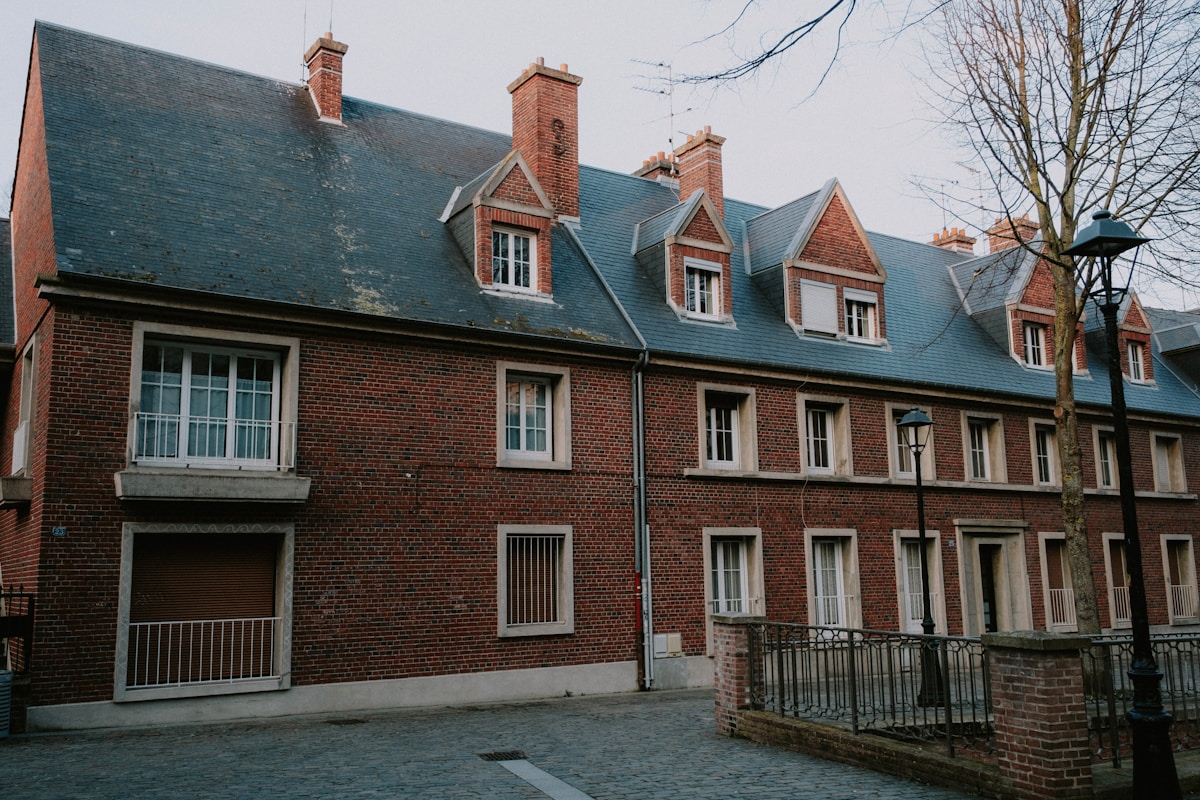 Bâtiment en briques rouges avec toits en ardoise verte.