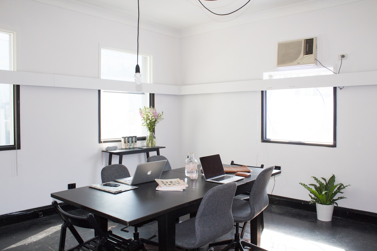 Bureau moderne avec ordinateurs portables et plante verte.