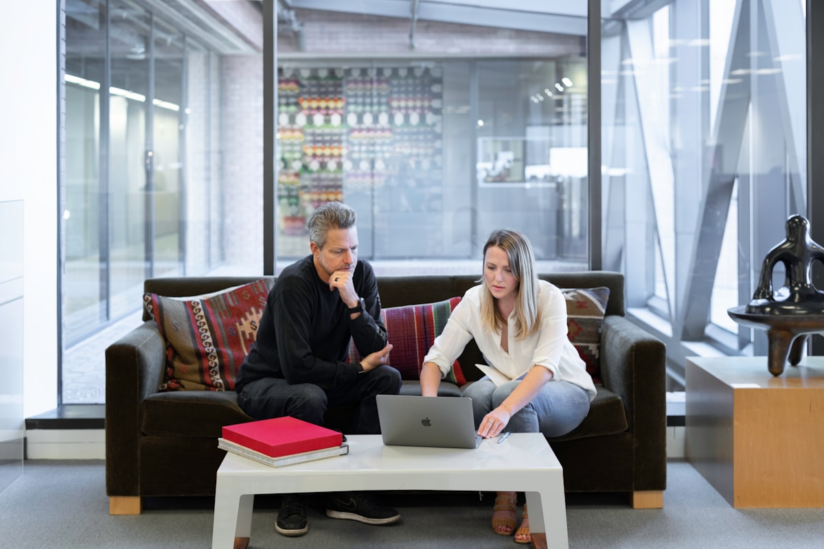 Deux personnes travaillant ensemble sur un ordinateur portable dans un bureau moderne.