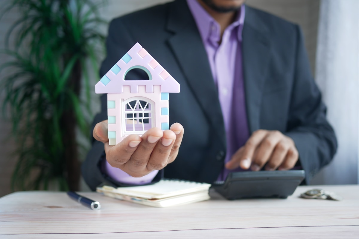 Homme d'affaires tenant une maquette de maison colorée.