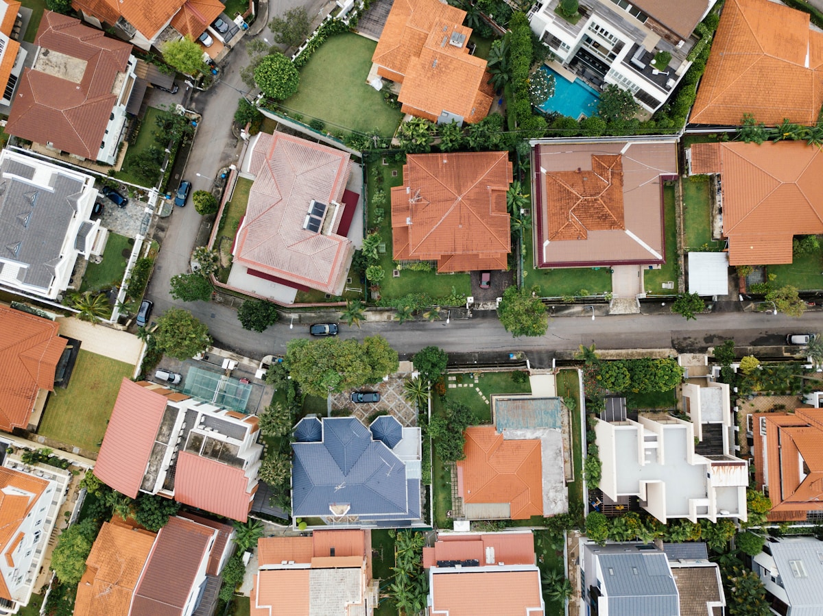 Vue aérienne d'un quartier résidentiel avec des maisons, des toits rouges et des jardins.
