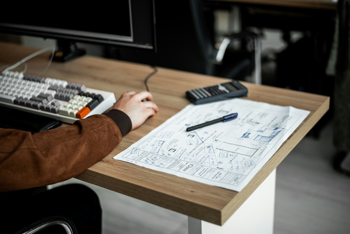 Personne travaillant à l’ordinateur sur des plans techniques annotés