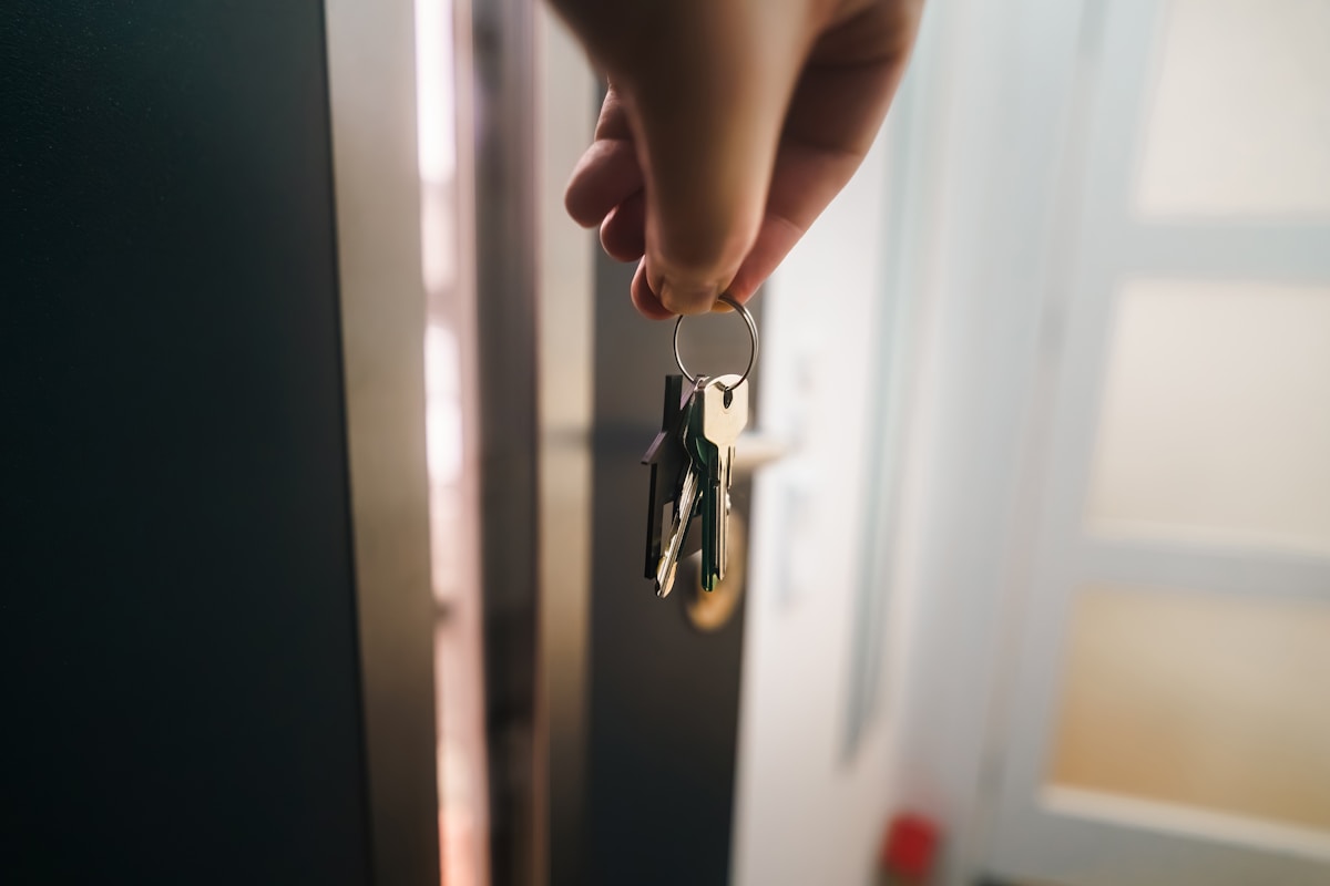 Clé de porte tenue dans la main près de la fenêtre.