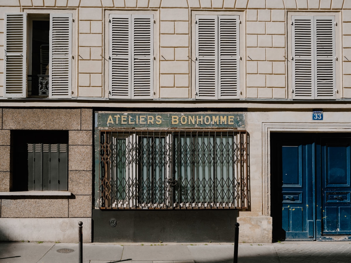 Façade de bâtiment avec volets en bois, enseigne "Ateliers Bonhomme".