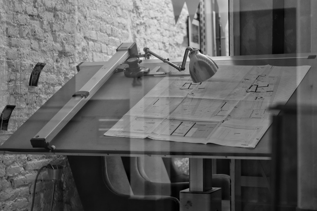 Établi de travail avec plans architecturaux et outils de conception.