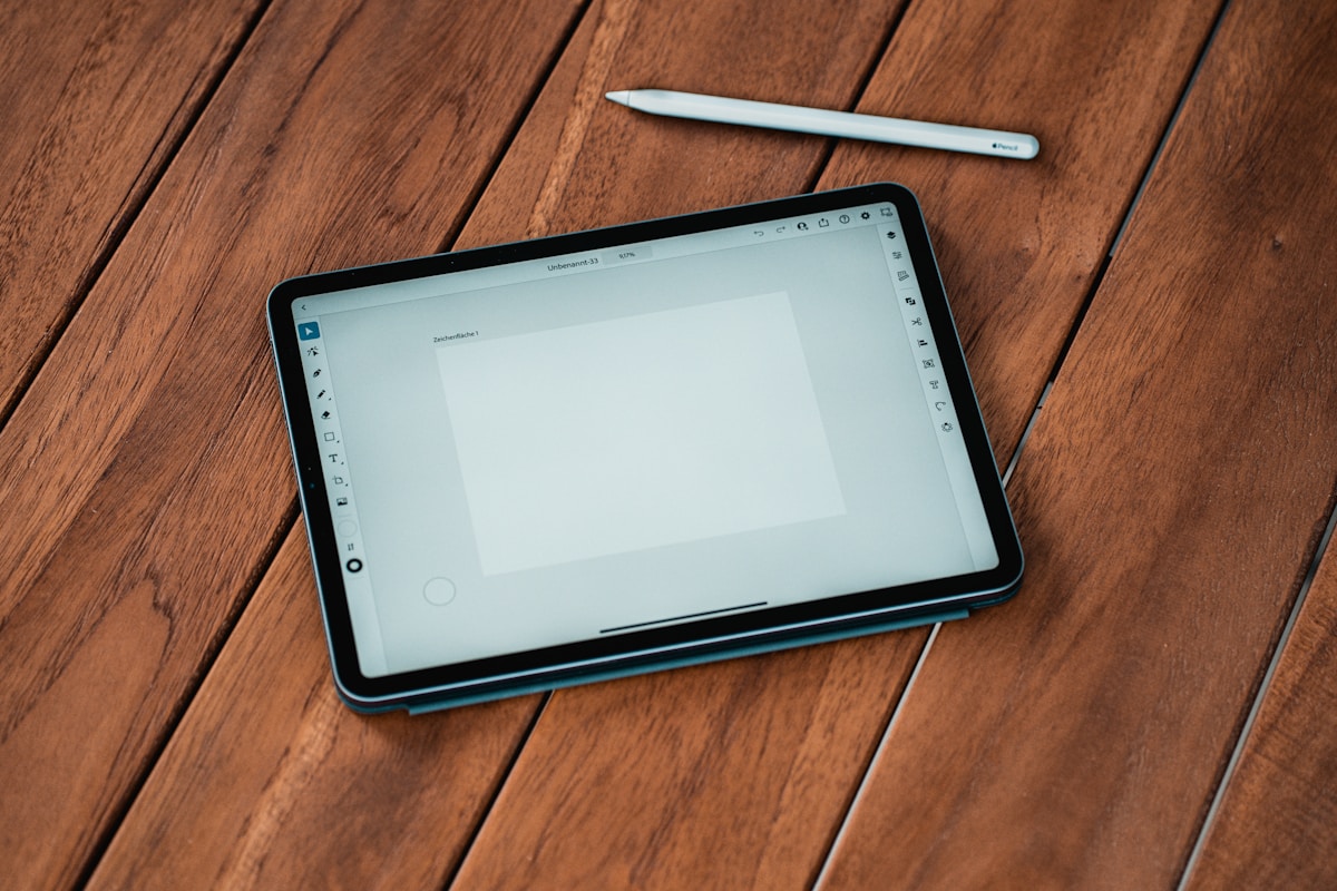 Tablette numérique avec stylet sur une surface en bois.