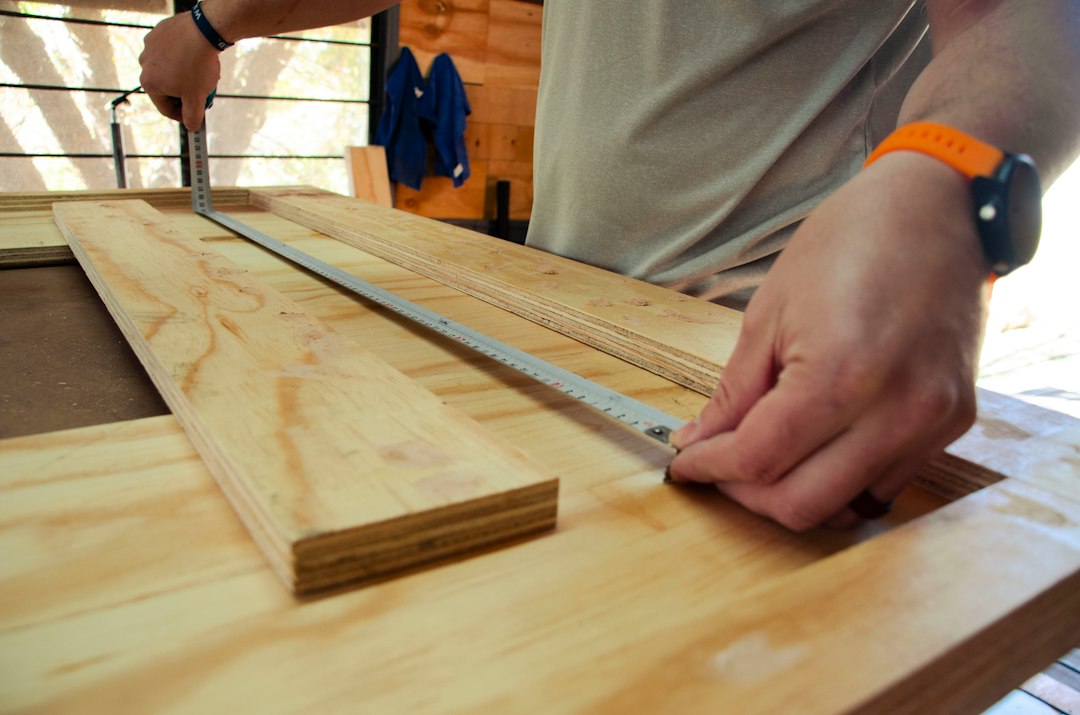 Carpentier mesure et trace des panneaux de bois pour portes de cuisine, atelier professionnel de rénovation façade cuisine bo