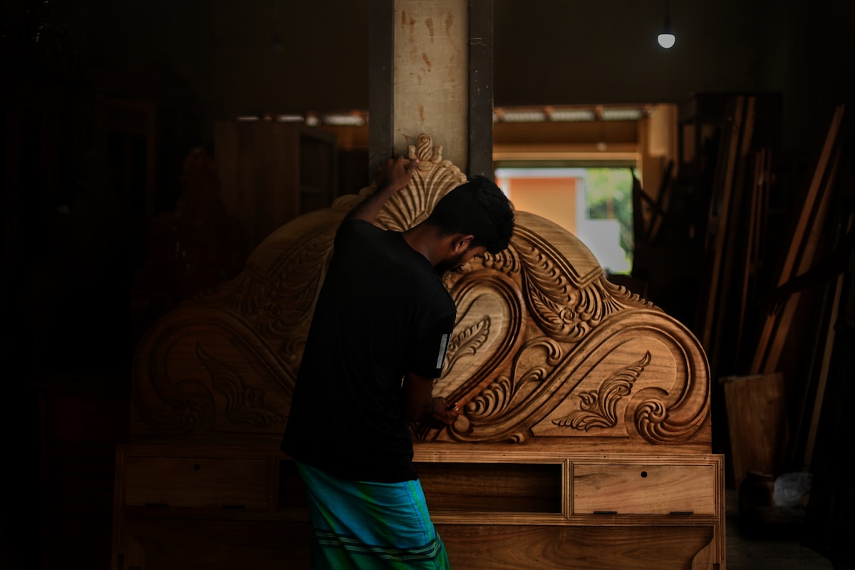 Homme contemplant une sculpture en bois sculptée de manière ornementale.
