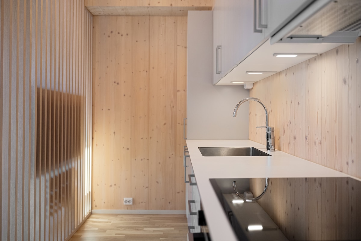 Cuisine moderne avec meubles en bois et évier en acier inoxydable.
