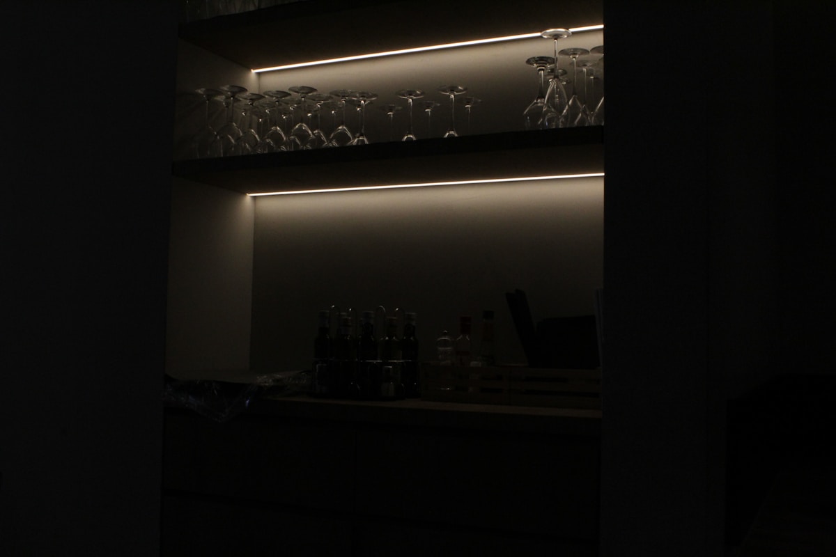 Étagères sombres avec des objets décoratifs et un éclairage indirect.