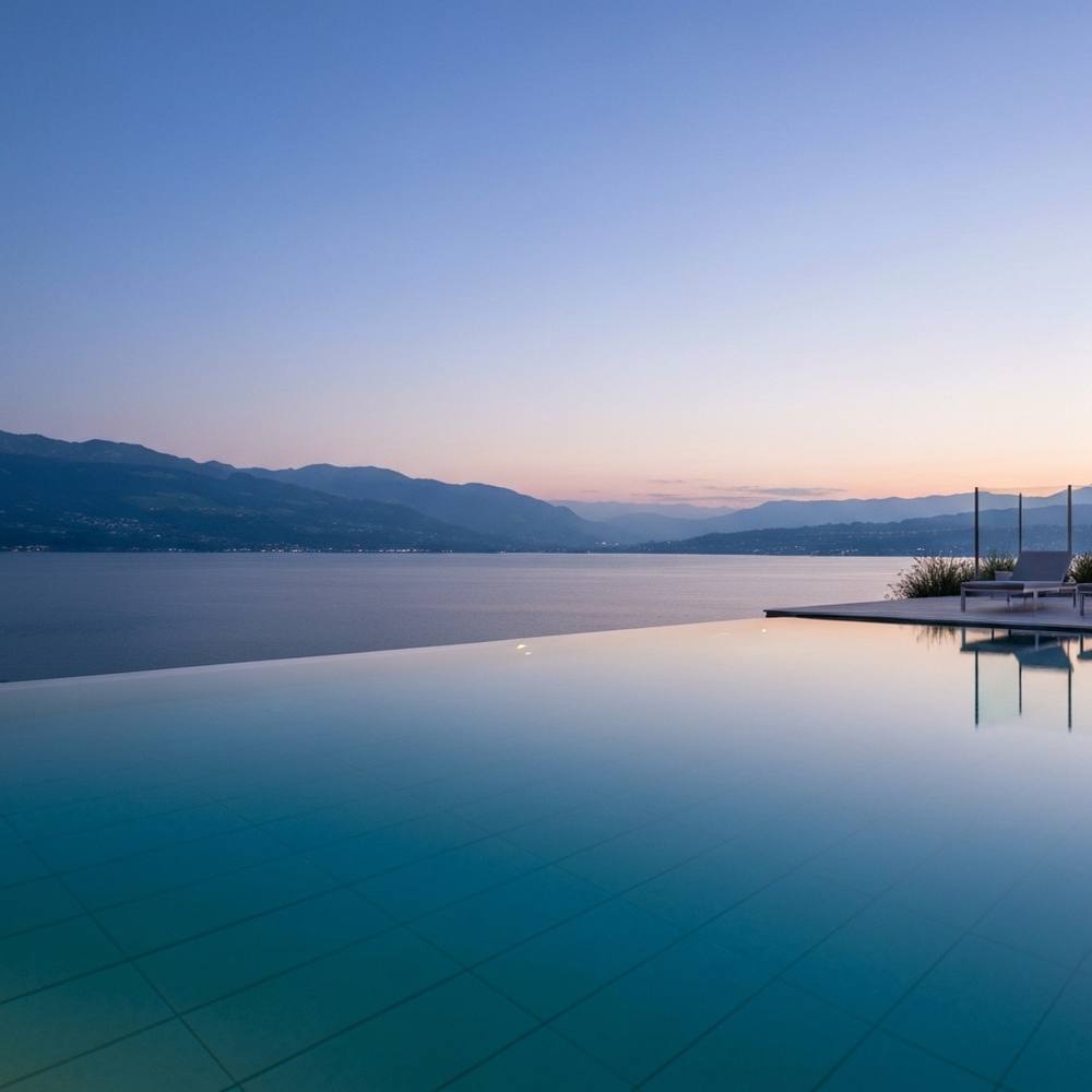 [Vue spectaculaire d'une piscine à débordement moderne surplombant le Lac Léman au crépuscule, avec des lumières d'ambiance.]