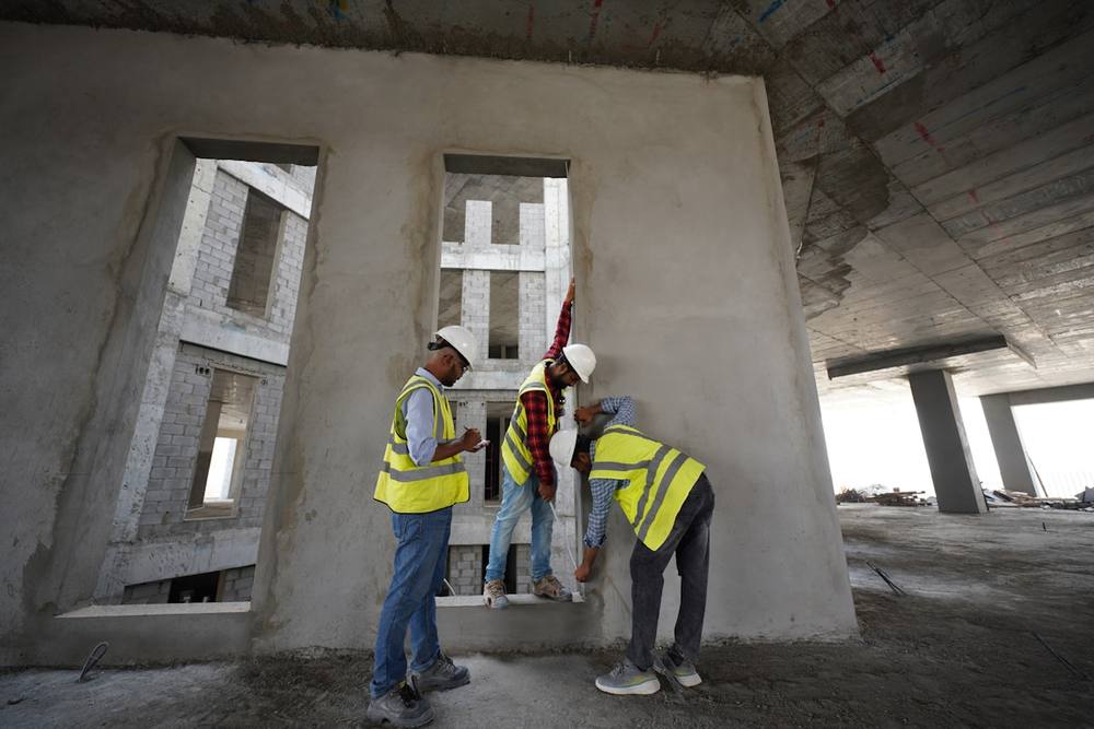 Trois ouvriers en gilets de sécurité inspectent un chantier de construction.