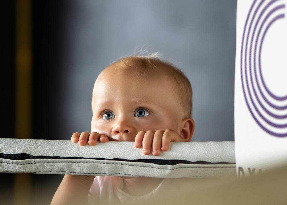 Bébé aux yeux bleus curieux, regardant par-dessus une surface.