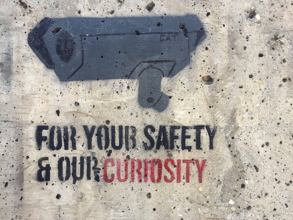 Panneau de sécurité et de curiosité sur un mur endommagé.