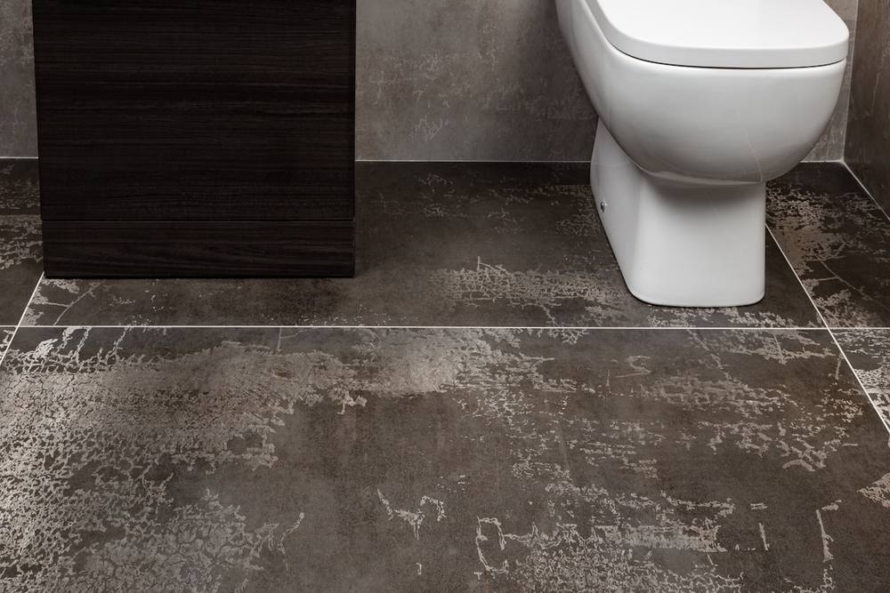 Salle de bain moderne avec carrelage gris foncé et toilette blanche.