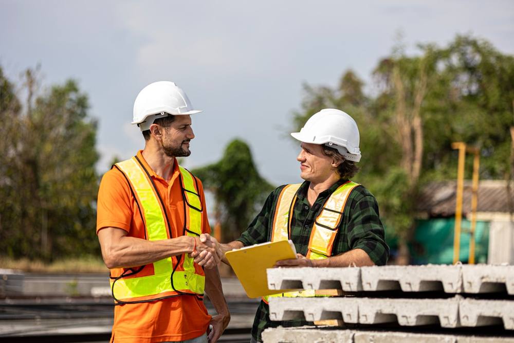 Deux travailleurs de la construction se serrant la main sur un chantier.