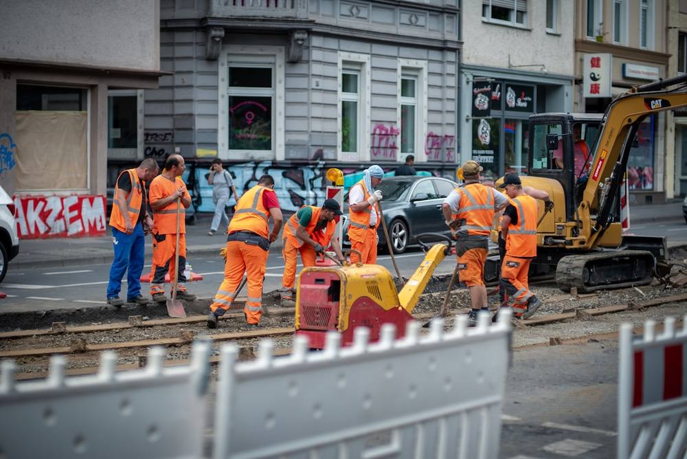 Groupe de travailleurs en gilets de sécurité orange effectuant des travaux de voirie sur la chaussée.