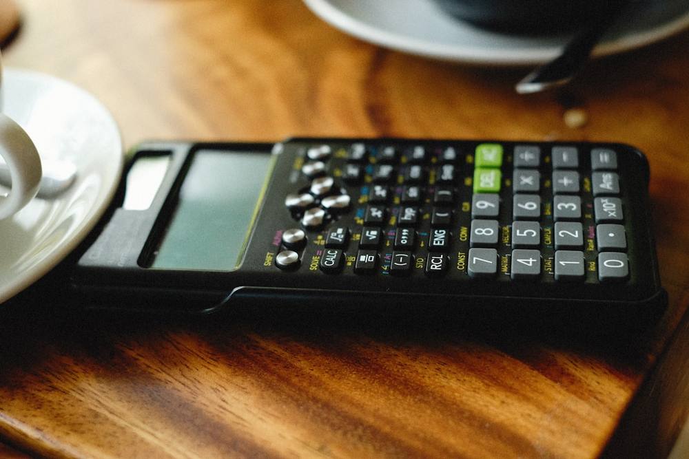 Une calculatrice posée sur une table en bois.