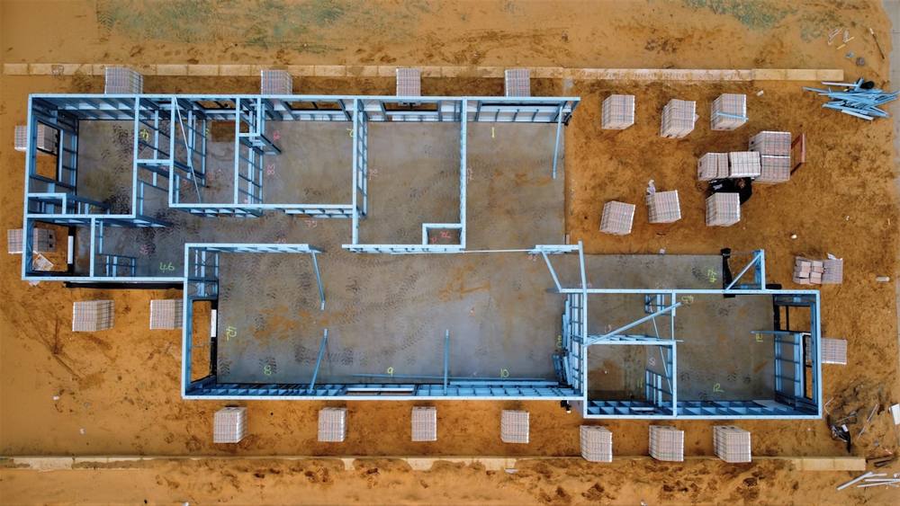 Chantier de construction avec structure métallique et matériaux empilés.