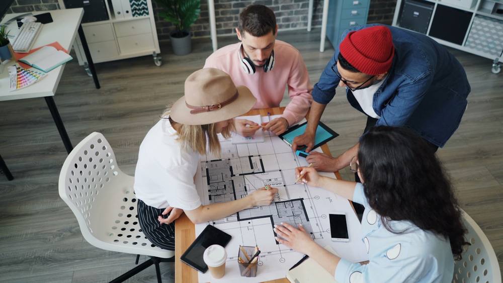 Équipe de concepteurs examinant des plans de construction sur une table.