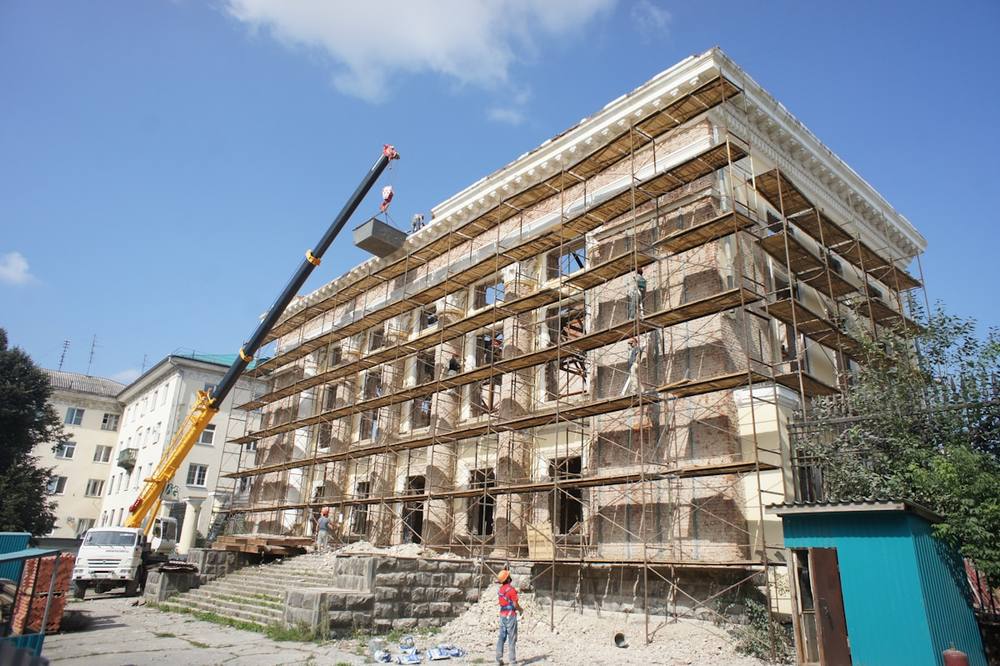 Bâtiment en rénovation avec échafaudage et ouvriers.