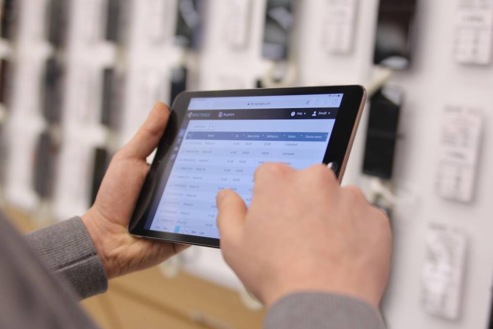 Mains tenant une tablette affichant une interface utilisateur avec des données.