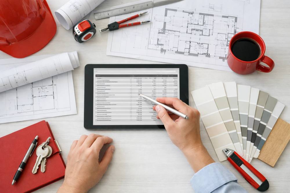 Consultant en rénovation professionnelle présentant un budget détaillé sur une tablette à des propriétaires mûrs dans un bureau suisse moderne et lumineux, plans architecturaux visibles sur la table, éclairage naturel à travers les fenêtres montrant l'architecture de Crissier.
