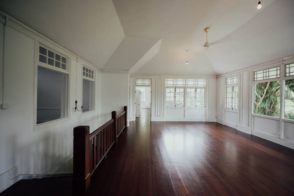 Vaste pièce lumineuse avec parquet en bois foncé et fenêtres panoramiques.