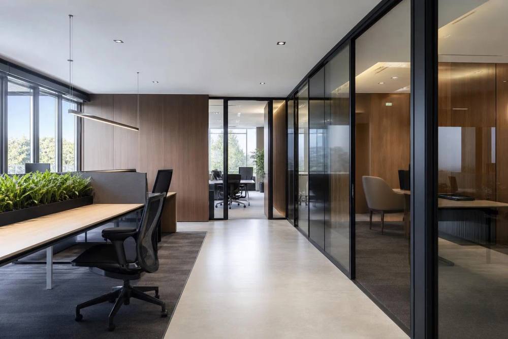 Espace de bureau moderne avec des meubles en bois et des cloisons vitrées.