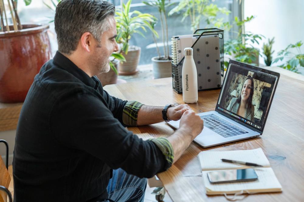 Un homme en pull noir utilisant un MacBook Pro.
