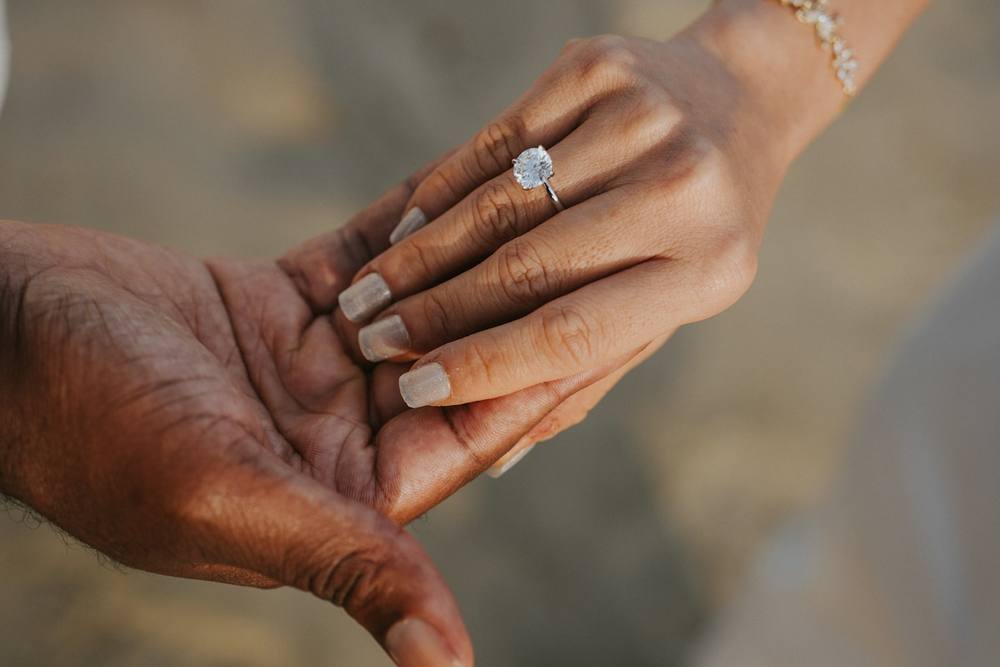 Une bague de fiançailles tenue dans les mains.